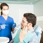 Dentist examining a patient with severe tooth pain during an emergency visit